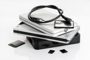 Group of external Hard disks and memory cards on white table. Data storage concept - Oryx Computers Qatar